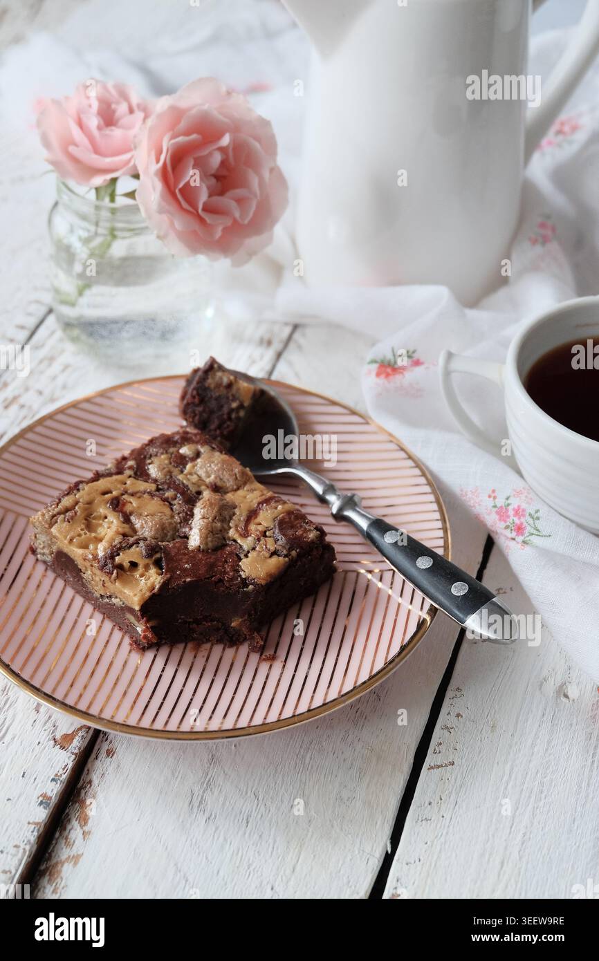 Stilvolle Portion Kakaokuchen umgeben von Blumen und antiker Teetasse Stockfoto