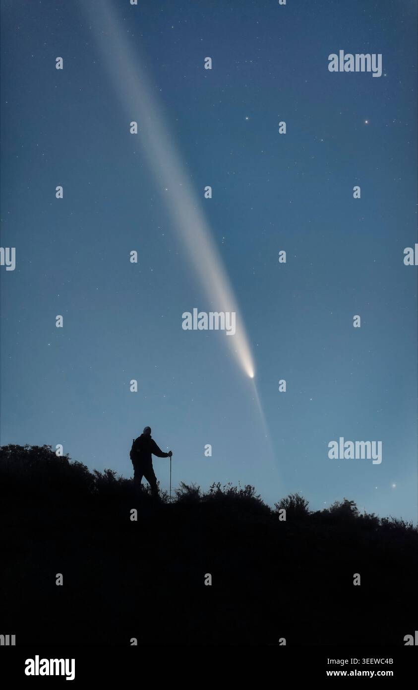 Man Silhouette am Berg beobachtet den Interstellaren Kometen C/2023 A3 Stockfoto