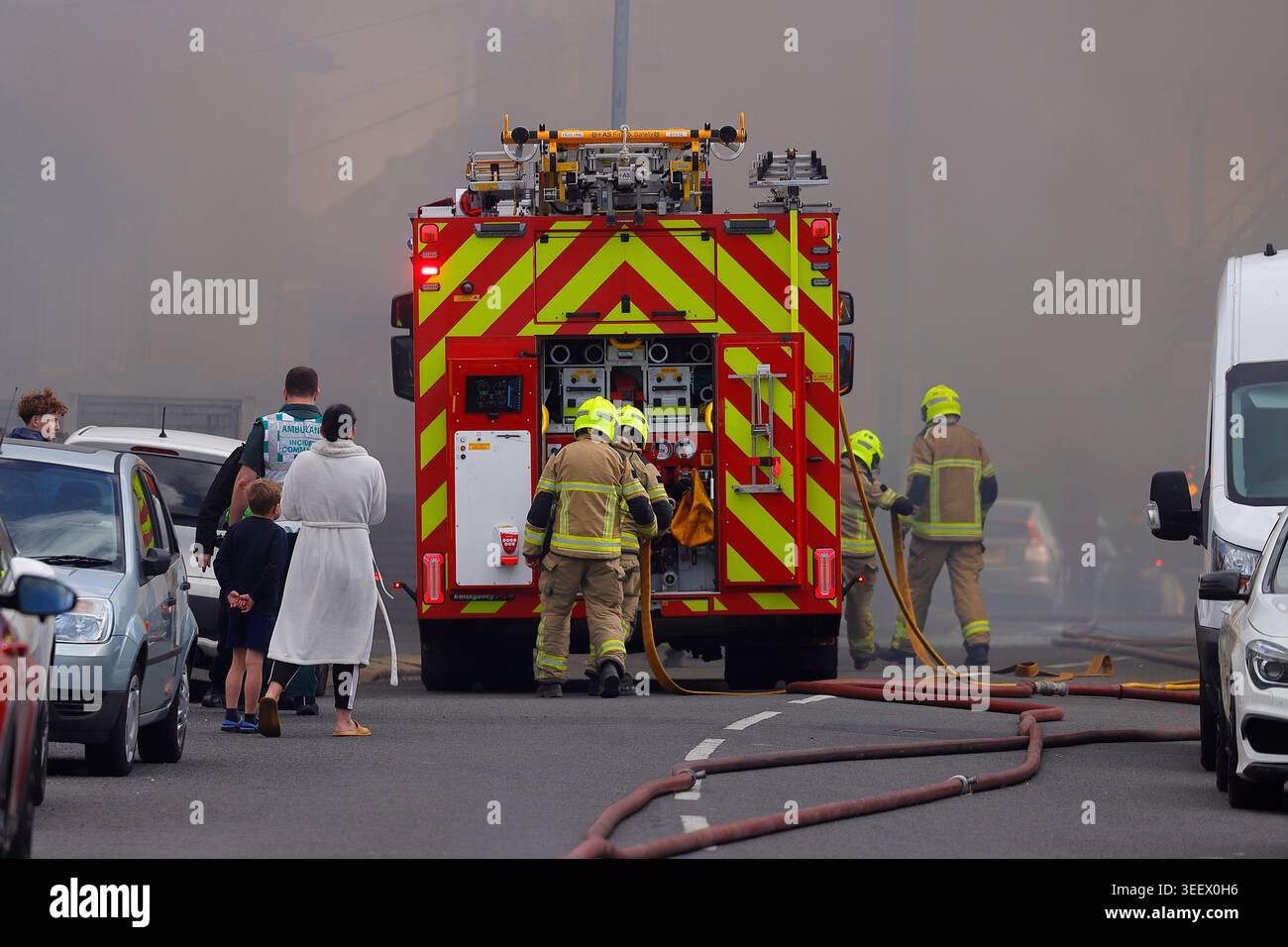 Feuerwehrmannschaft und Mitglieder der Öffentlichkeit am Ort eines Brandes im ehemaligen Festival Foods Warehouse in Osmandthorpe, Leeds, West Yorkshire, Großbritannien Stockfoto