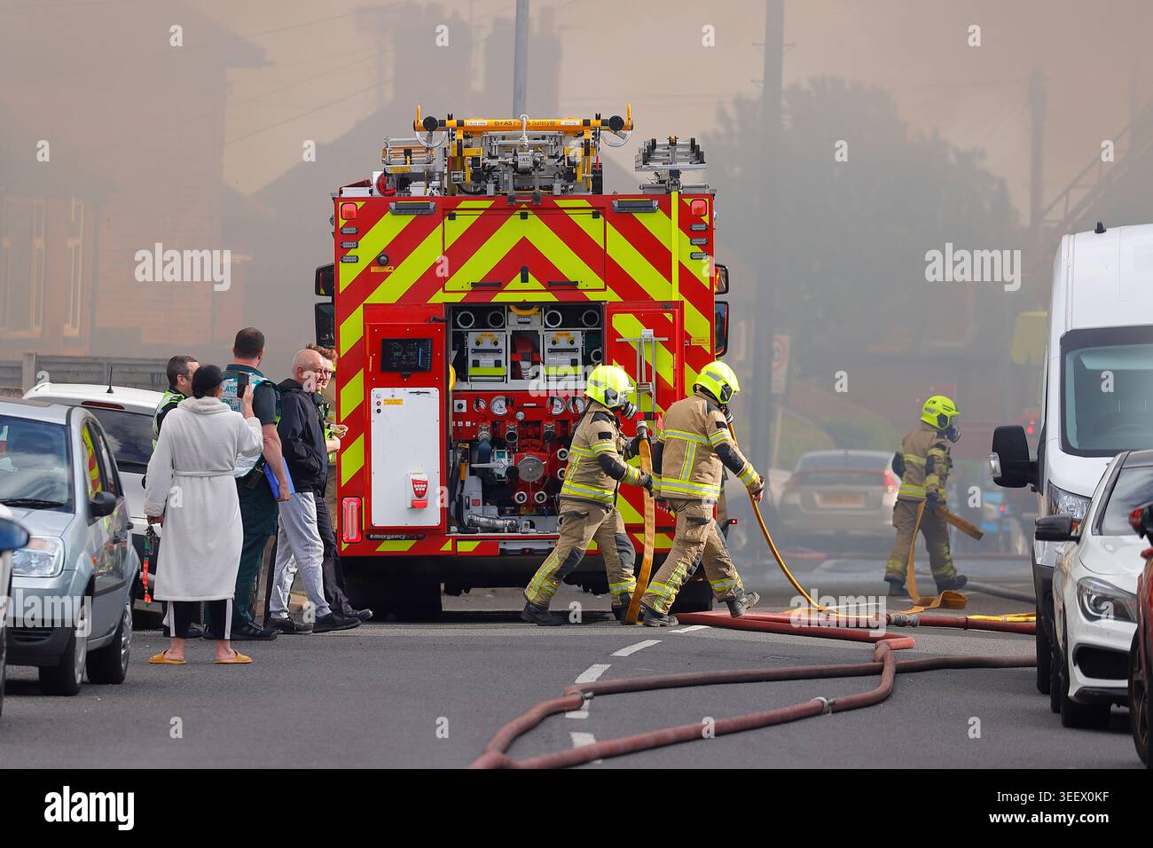 Feuerwehrmannschaft und Mitglieder der Öffentlichkeit am Ort eines Brandes im ehemaligen Festival Foods Warehouse in Osmandthorpe, Leeds, West Yorkshire, Großbritannien Stockfoto
