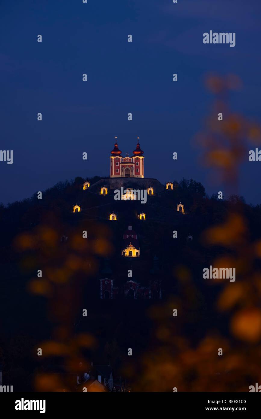 Historischer Calvary Komplex, der in der Abenddämmerung auf einem Hügel glänzt und durch Herbstlaub blickt Stockfoto