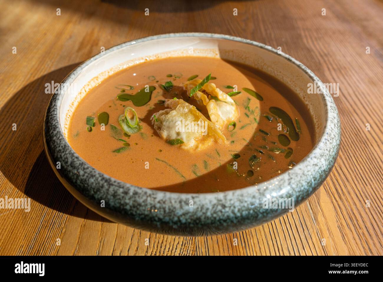 Nepalesische Momo Jhol Achar Knödelsuppe, gebratene Gyoza-Brühe, scharfe Tomaten-Momo-Suppe in exquisitem Restaurant Bowl im Sonnenlicht Closeup Stockfoto