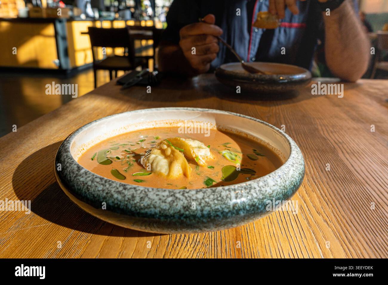 Nepalesische Momo Jhol Achar Knödelsuppe, gebratene Gyoza-Brühe, scharfe Tomaten-Momo-Suppe in exquisitem Restaurant Bowl im Sonnenlicht Closeup Stockfoto