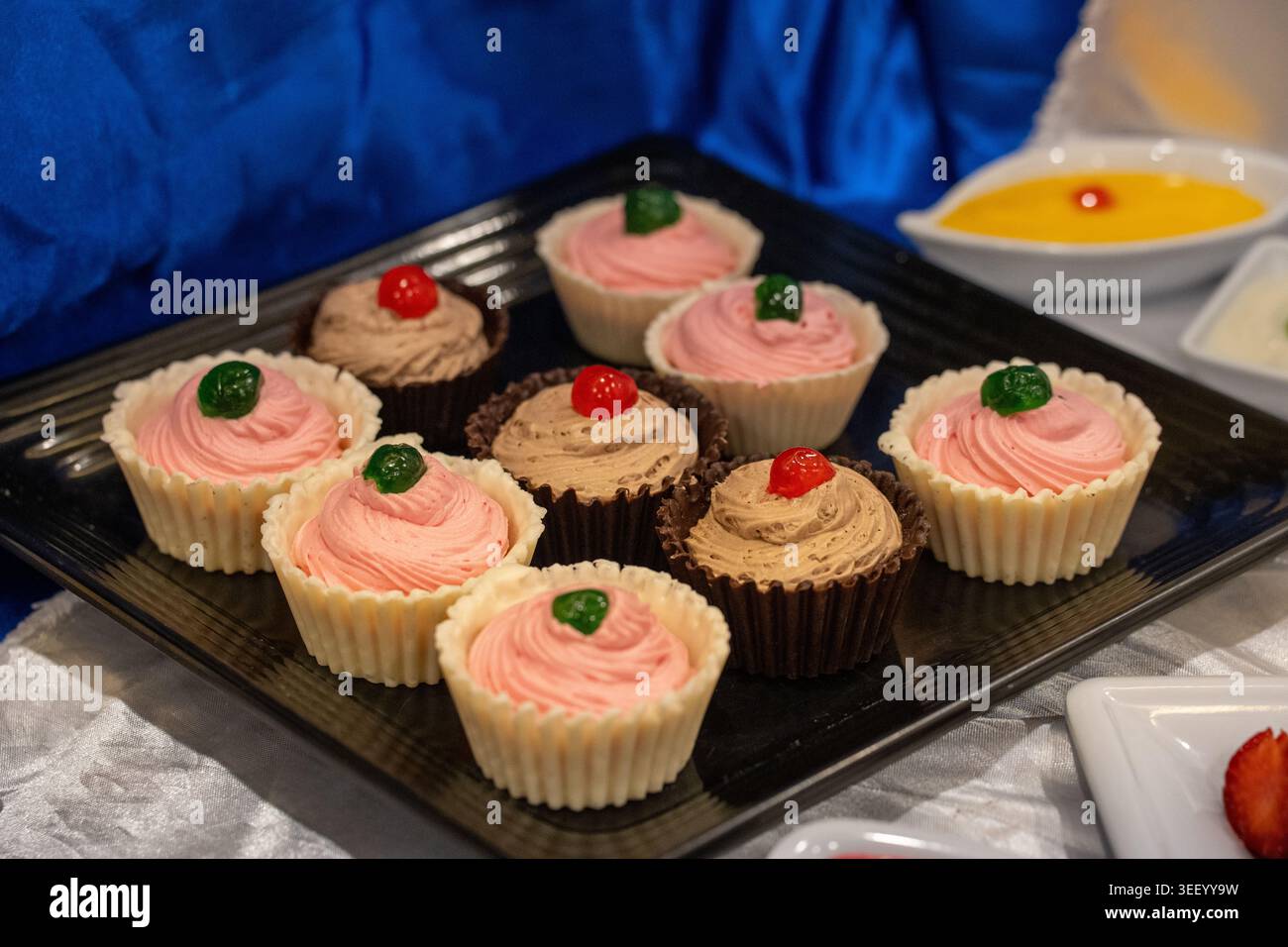 Köstliche Desserttörtchen mit Schokolade und rosa Zuckerguss auf einer schwarzen Platte Stockfoto