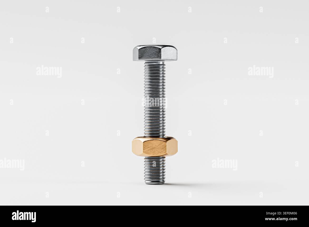 Eine Nahansicht eines Metallbolzens mit einer glänzenden Oberfläche und einer kontrastierenden Goldmutter vor einem neutralen Hintergrund. Stockfoto