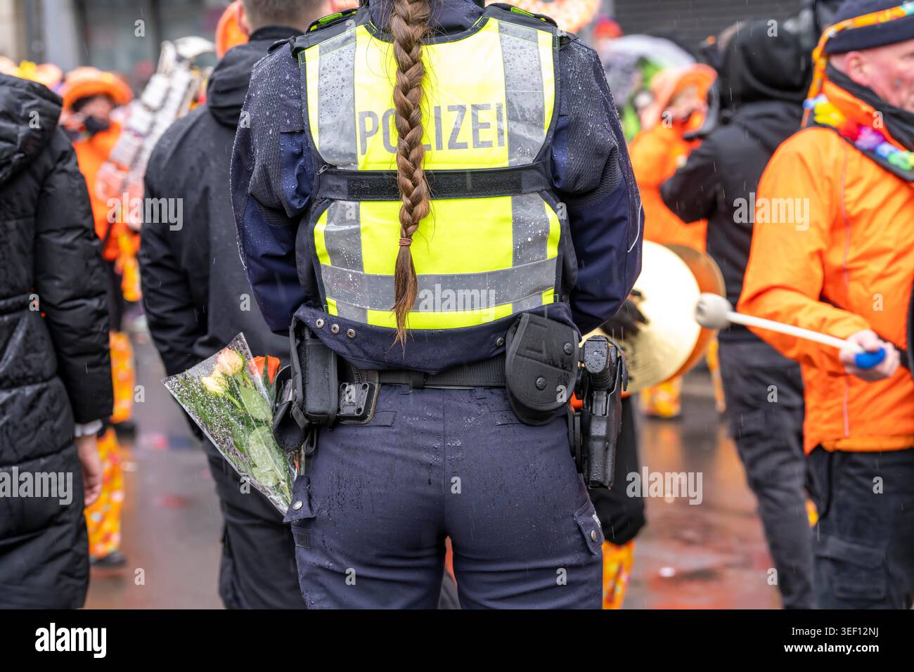 Rosenmontagszug in Düsseldorf, Einsatzkräfte, sichern, begleiten den Umzug, Polizistin mit geschenkten Blumen Sträußchen, Strüsschen, bei teils stark Stockfoto