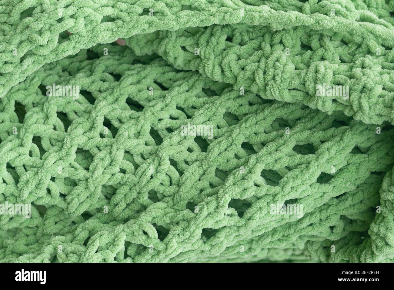 Grüne Plüschstrickdecke. Hintergrund aus weichem Chenille-Garn. Stockfoto