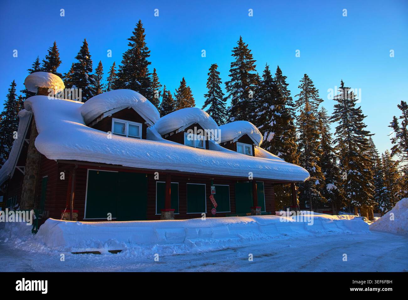 Winterhütte mit tiefem Schnee im Wald bei Sonnenuntergang in Alberta Kanada Stockfoto