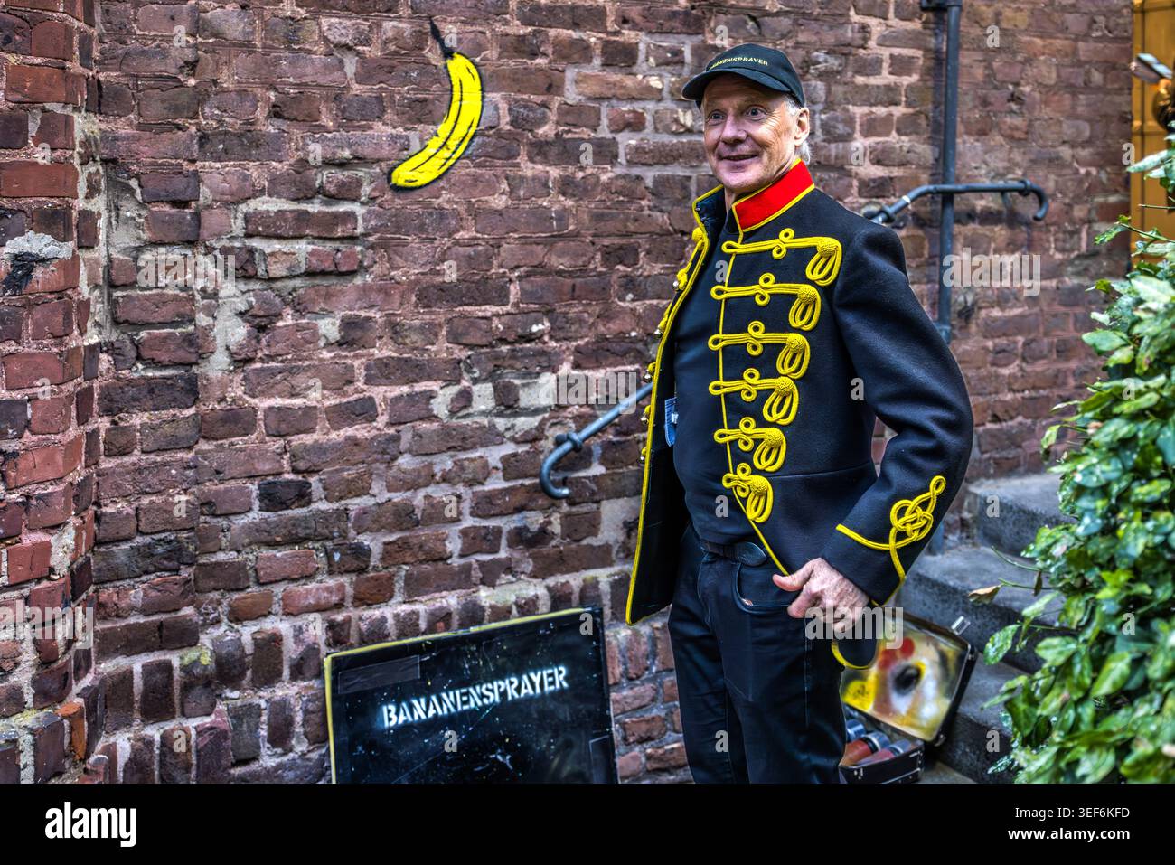 Thomas Baumgärtel spricht während der Spritzmalerei über sein Leben als Bananenspray-Maler. Für das Großprojekt „Niederrheintour“ trägt er zu den Ausstellungseröffnungen ein Remake einer Jimi Hendrix Husarenjacke. Grevenbroich, Nordrhein-Westfalen, Deutschland Stockfoto