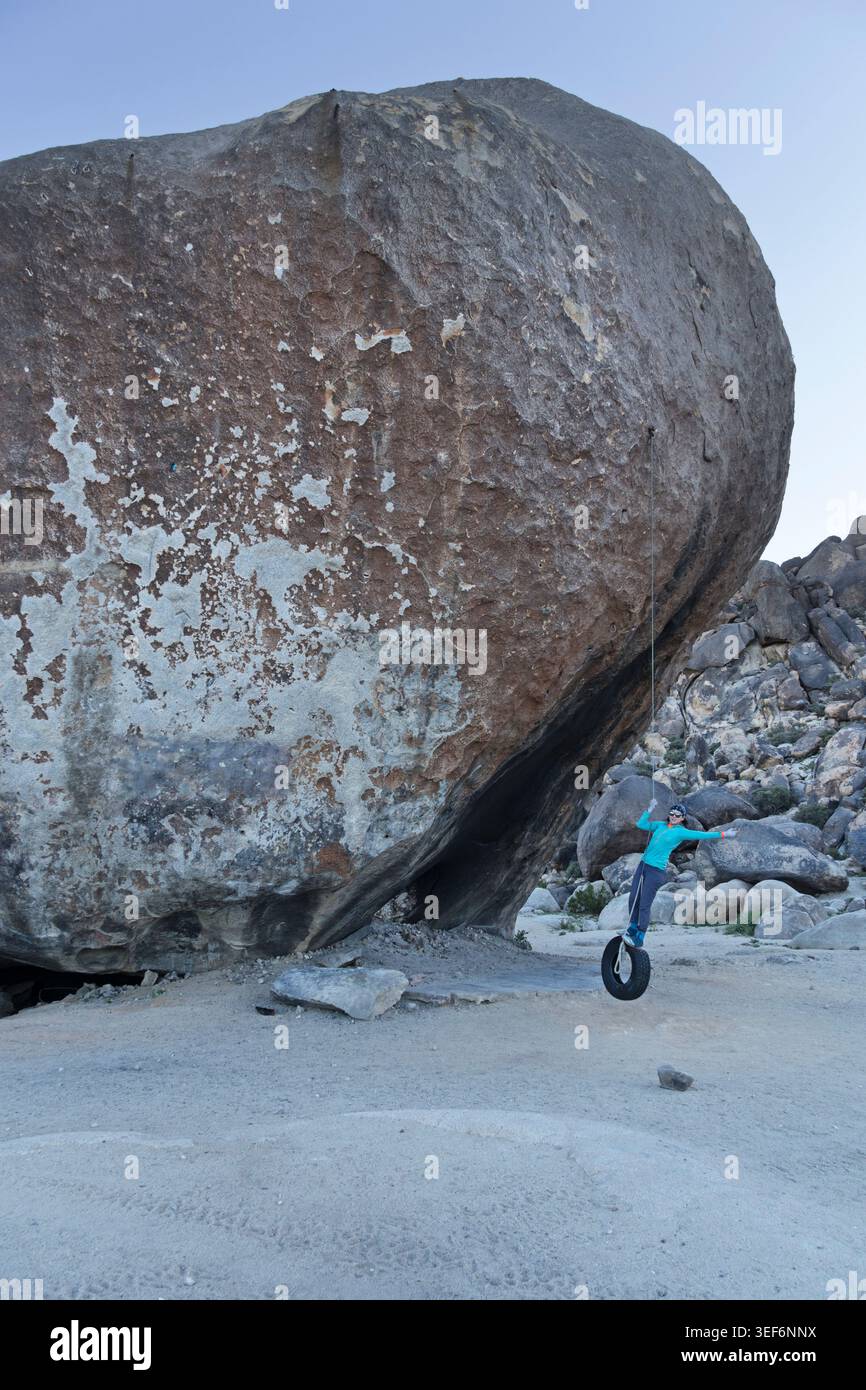 Eine Frau schwingt auf einer Reifenschaukel, die am Giant Rock in der Nähe von Landers California hängt Stockfoto