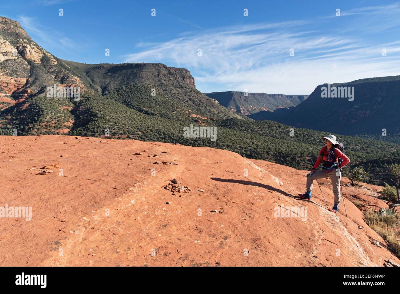 Frau, die auf das Deck des Steamboat Rock in der Nähe von Sedona Arizona mit dem Oak Creek Canyon im Hintergrund wandert Stockfoto