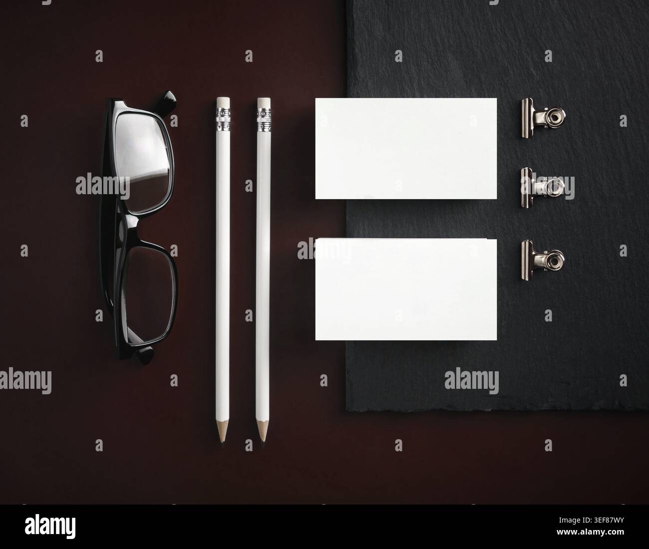 Vorlage für Firmenunterlagen. Leere Visitenkarte, Bleistifte, Brille und Binderclips. Branding-Mock-Up. Flache Lagen Stockfoto