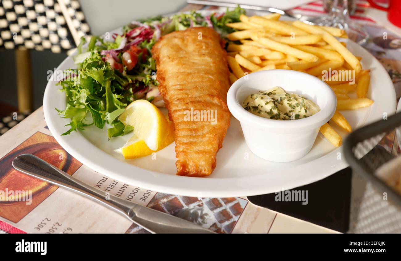 Traditioneller Teller mit Fisch und Chips, serviert mit knusprigen goldenen Pommes frites und Tatarsauce. Knuspriges Kabeljaufilet mit knusprigen Fritten Stockfoto