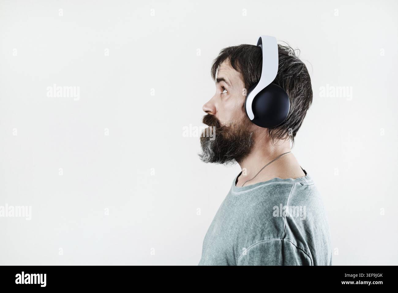 Seitenansicht eines bärtigen Mannes, der Musik über Kopfhörer hört Stockfoto