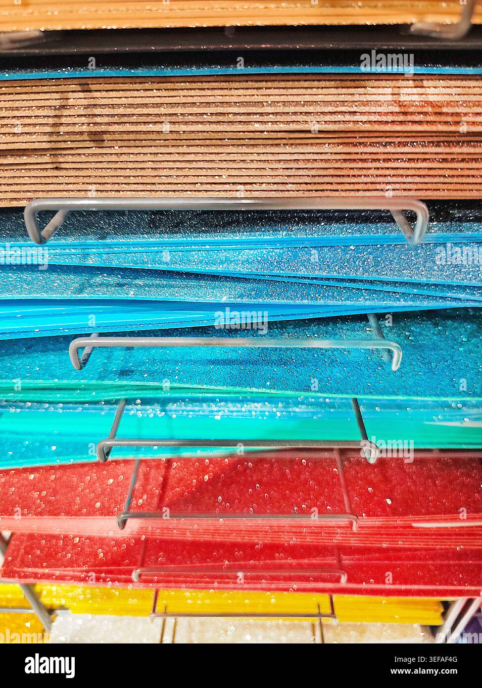Stapel von bunten Filztextilien, Papier in Orange, Rot, Grün, Braun, und blau auf einem Metallregal. Handwerkliche Materialien, die in einem Geschäft ausgestellt werden, ideal für Stockfoto