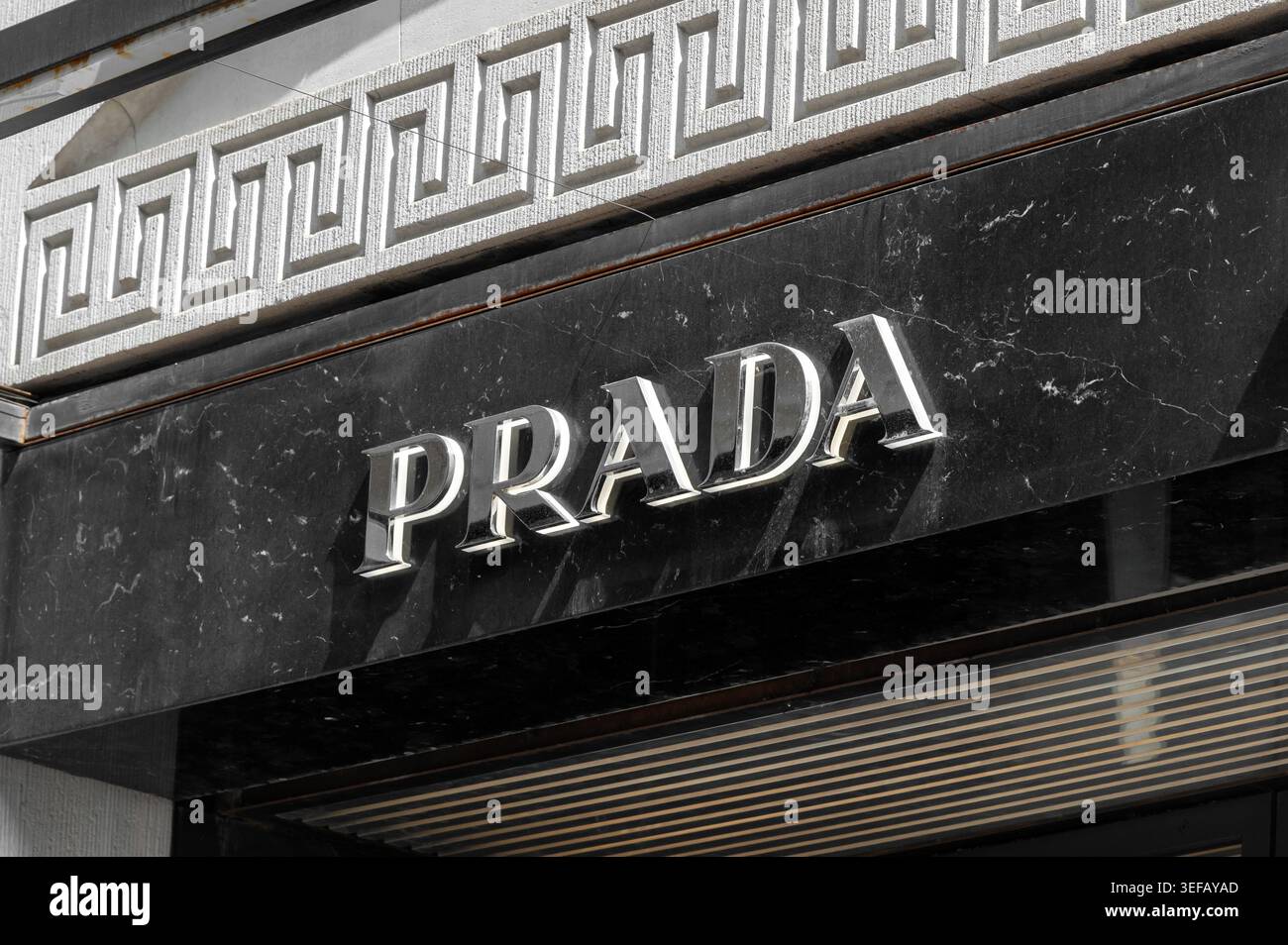 Mailand, Lombardei, Italien - 22. April 2026: Logo der Marke Prada auf einer Fassade aus schwarzem Marmor mit dekorativem Relief Stockfoto