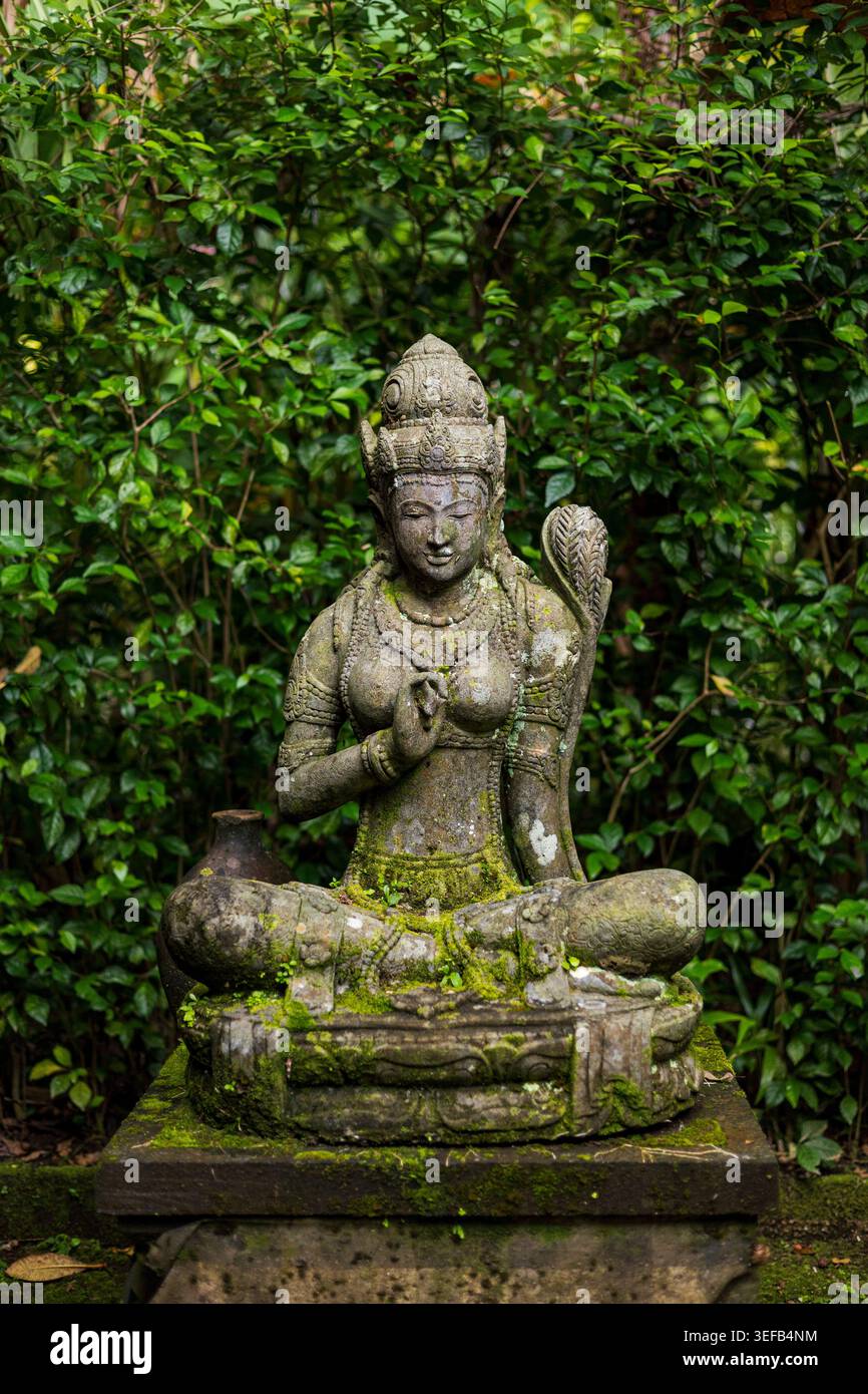 Steinstatue einer sitzenden weiblichen Gottheit im Garten, Bali, Indonesien Stockfoto