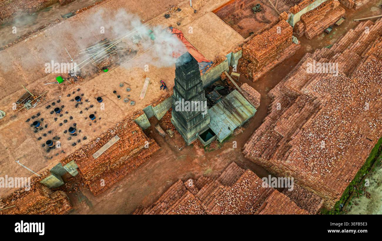 Ziegelherstellung in einer Fabrik mit gestapelten Ziegeln und einem Schornstein in Bangladesch Stockfoto