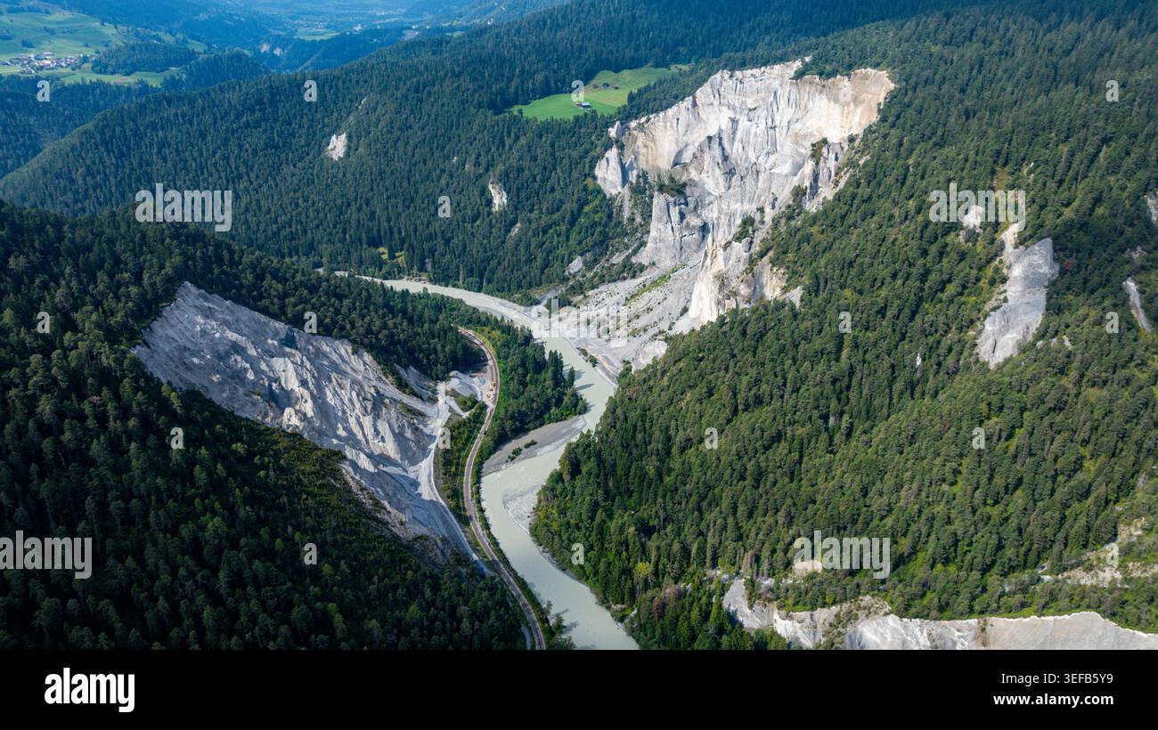 Aus der Vogelperspektive werden die Kurven der Rheinschlucht, umgeben von grünen Hügeln und steilen Klippen in der Schweiz bei Tageslicht, erfasst Stockfoto