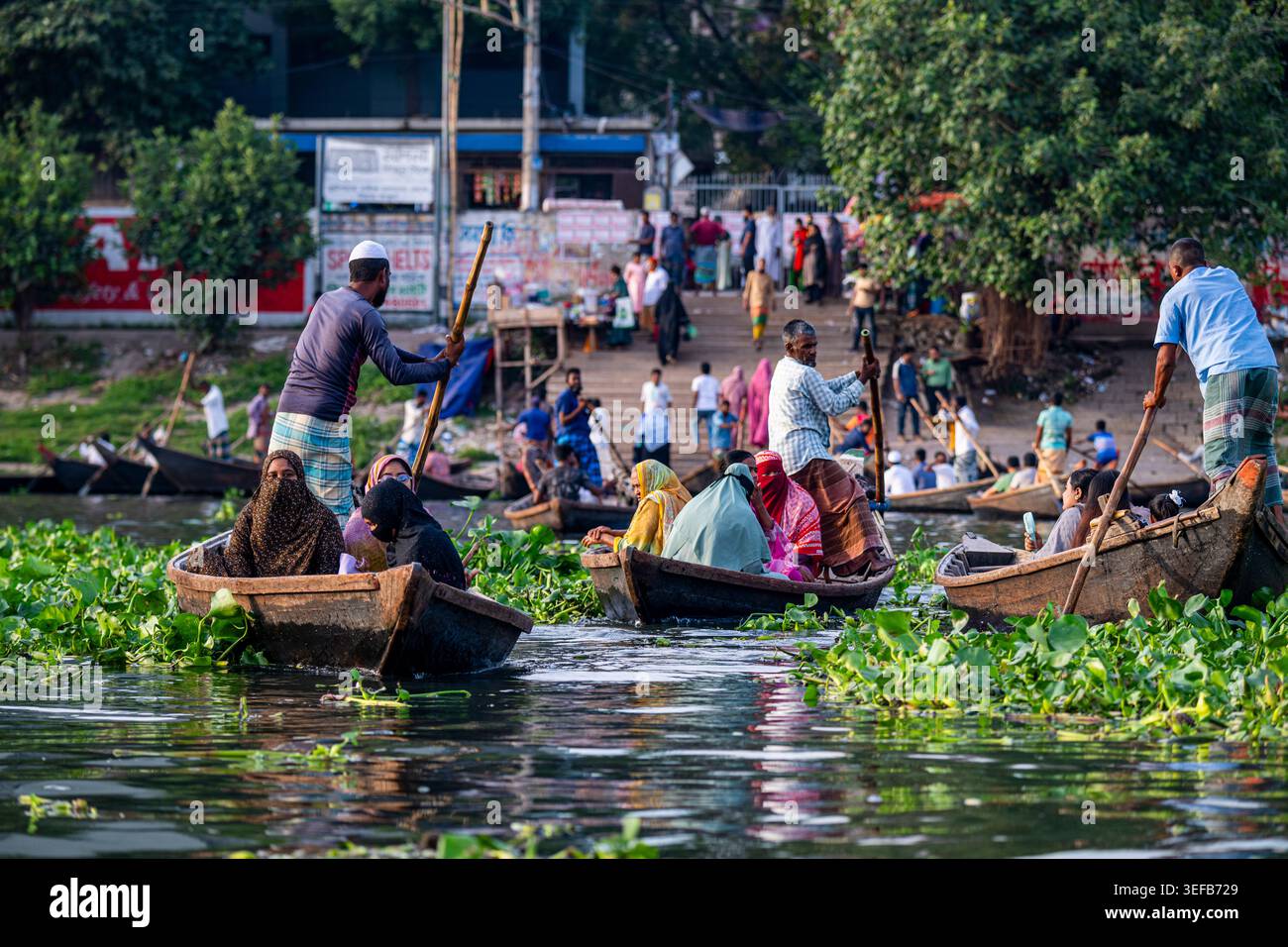 Boote fahren auf dem Buriganga River, während Menschen tägliche Aktivitäten in Dhaka, Bangladesch, durchführen Stockfoto
