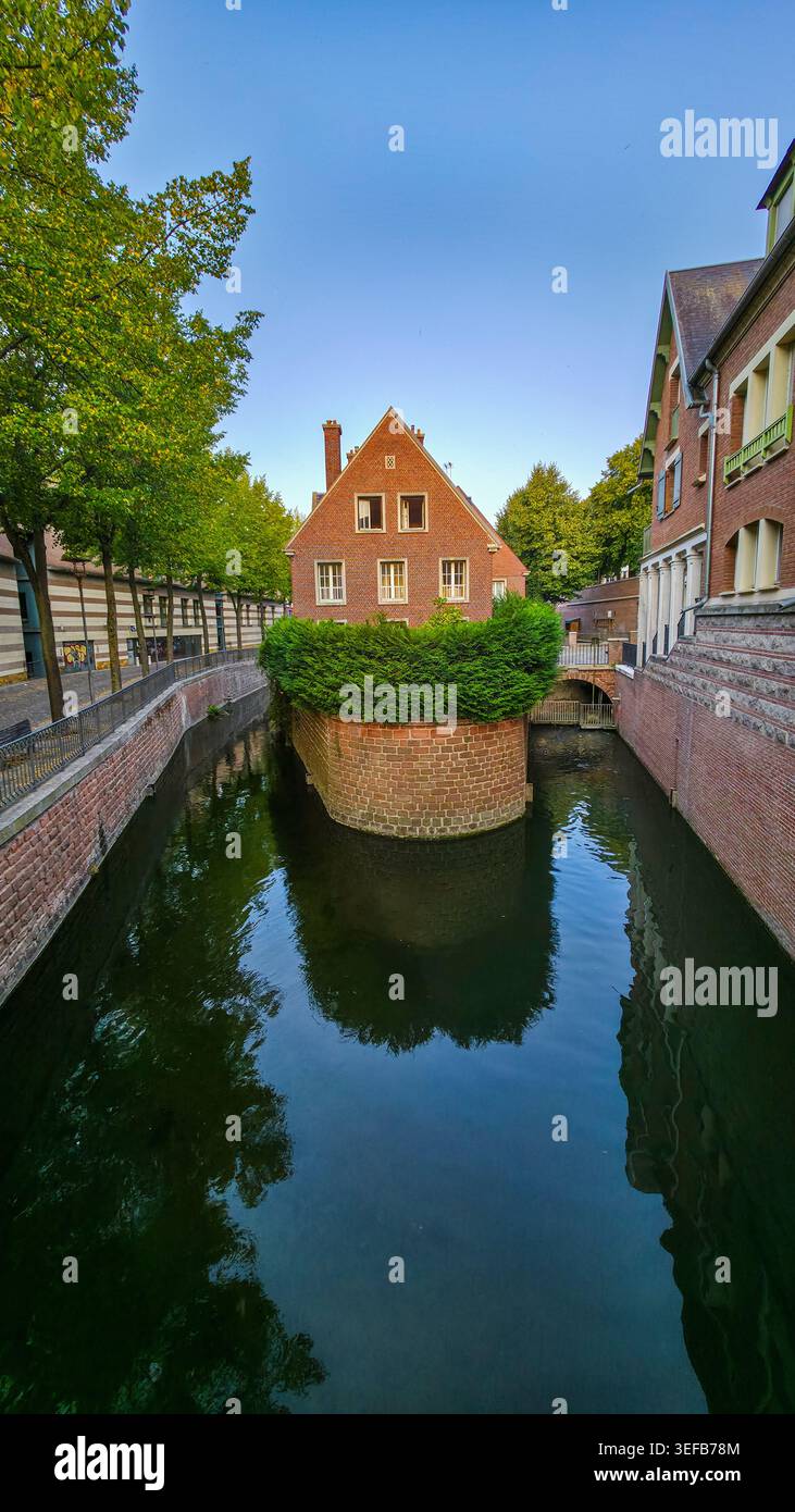 Ein kleiner Kanal fließt durch Bäume in der Nähe von Haus in Amiens, Frankreich an einem klaren Tag mit blauem Himmel Stockfoto