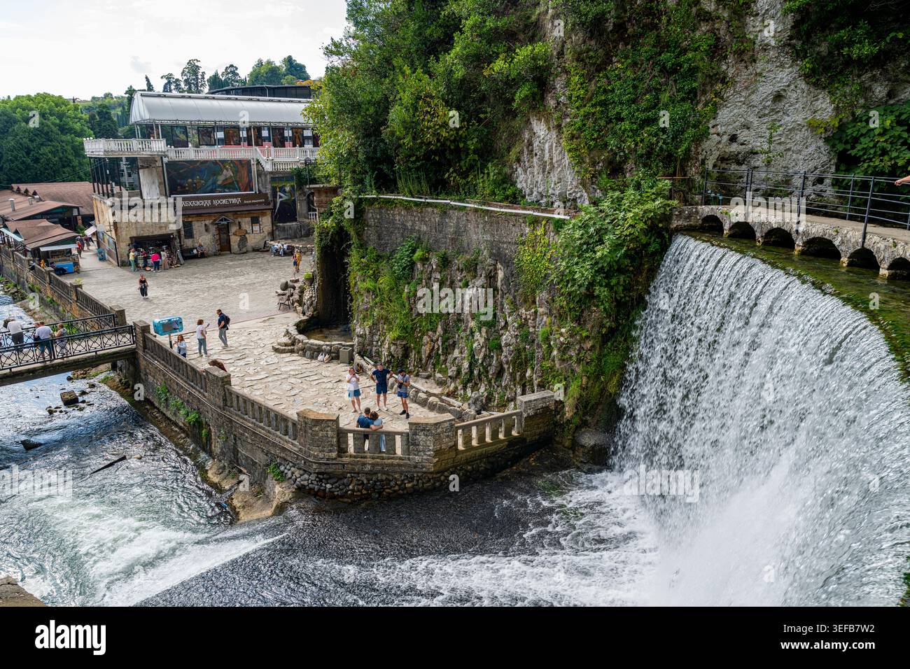 Besucher erkunden den künstlichen Wasserfall und die Umgebung in New Marathon, einem Ort, der für den Tourismus in Russland beliebt ist Stockfoto