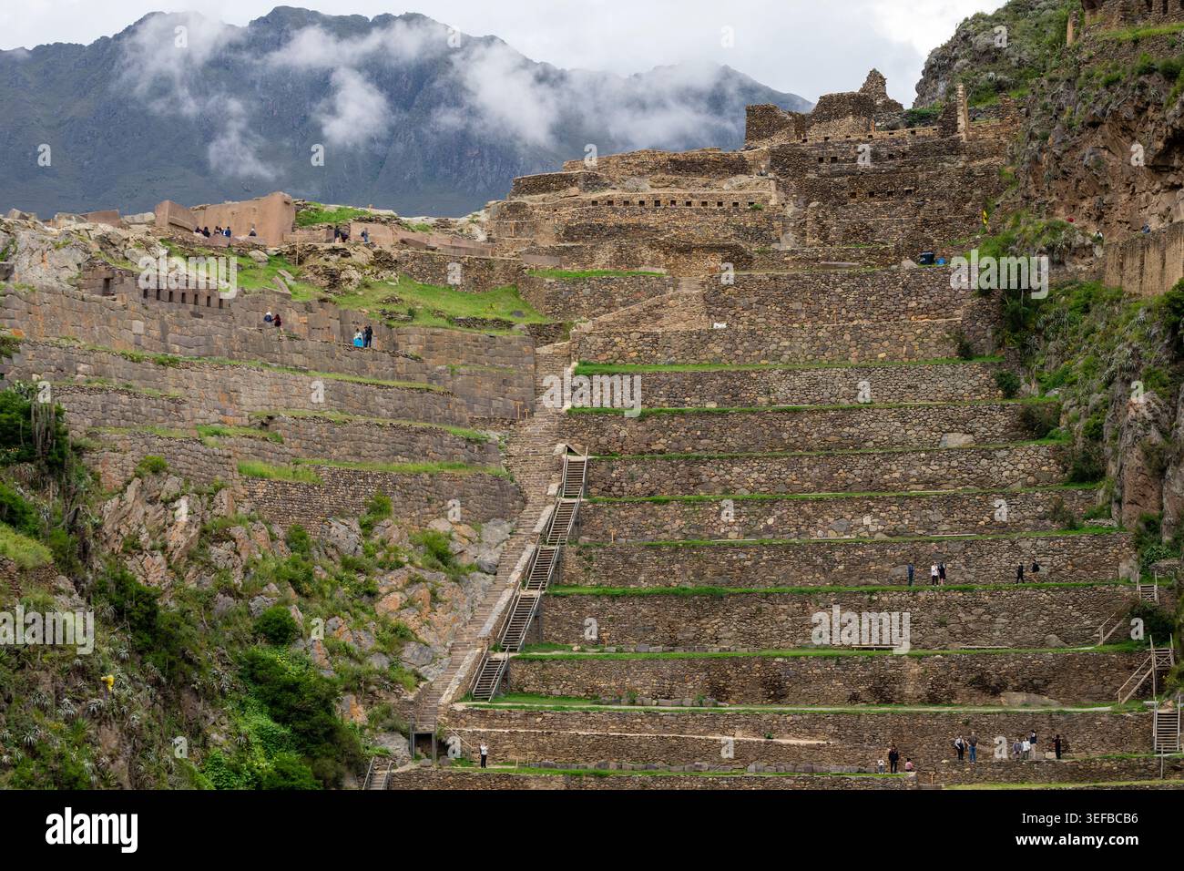 Ollantaytambo zeigt an einem bewölkten Tag in den Anden Perus terrassenförmig angelegte landwirtschaftliche Gebiete und alte Steinstrukturen Stockfoto