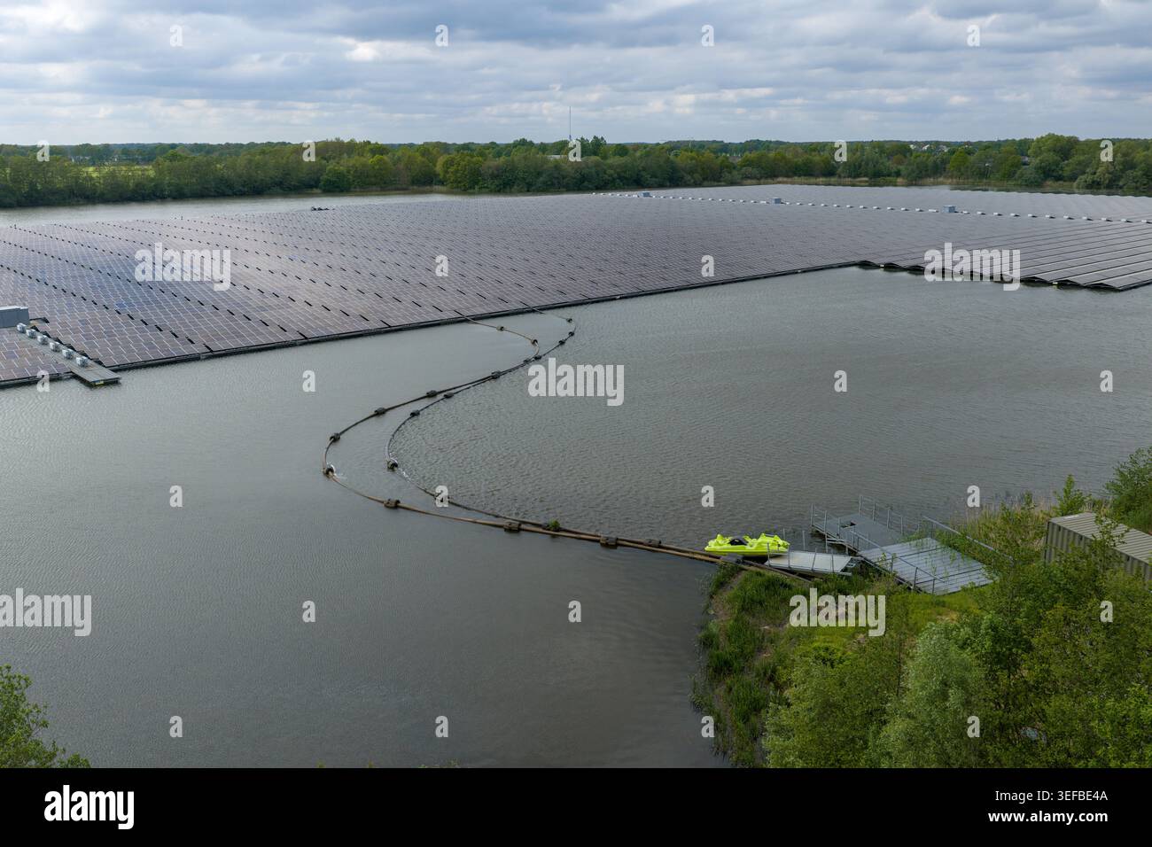 Luftaufnahme eines großen schwimmenden Solarparks auf einem See, umgeben von üppigen grünen Bäumen in Beilen, Drenthe, Niederlande. Stockfoto