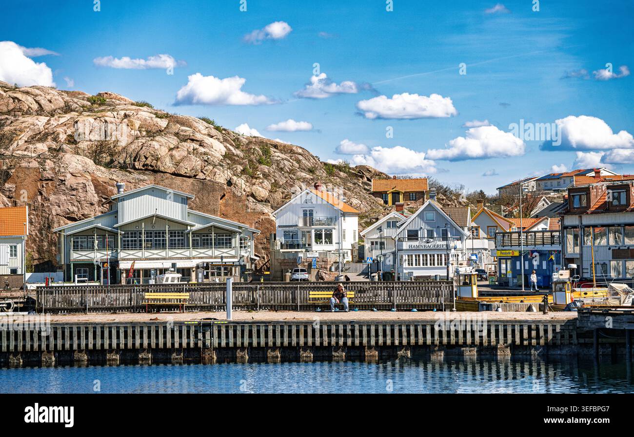 Farbenfrohe Häuser am Wasser entlang der Berghüste unter blauem Himmel, Kungshamn, Schweden Stockfoto