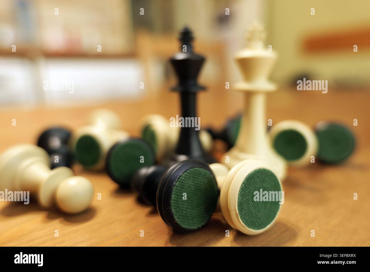 Auf einem Holztisch verstreute Schachfiguren mit den schwarz-weißen Königen, die zwischen den gefallenen Stücken stehen, symbolisieren Konzepte von Strategie und Wettbewerb Stockfoto