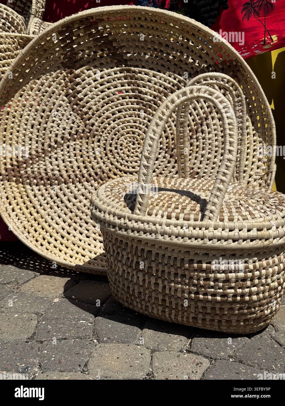 Traditionelle handgefertigte Korbkörbe und Strohhüte werden als Souvenirs auf einem jamaikanischen Markt ausgestellt. - Smartphone-aufgenommenes Stockfoto