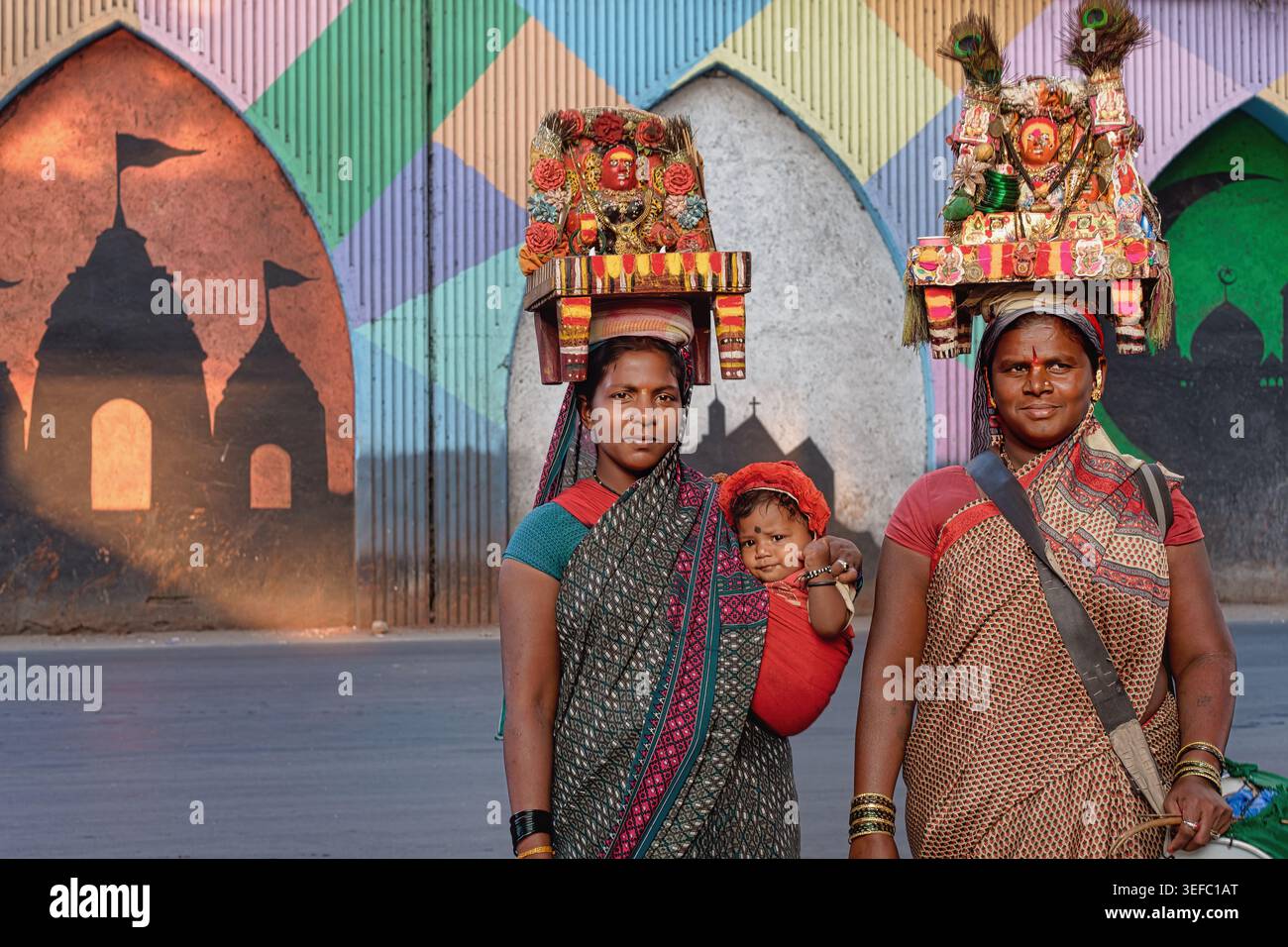Anhänger der Göttin Yellamma tragen ihre Bilder auf dem Kopf und bitten um Spenden in Mumbai, Indien. Die Person auf r ist ein Hijra, Eunuch oder Transgender Stockfoto