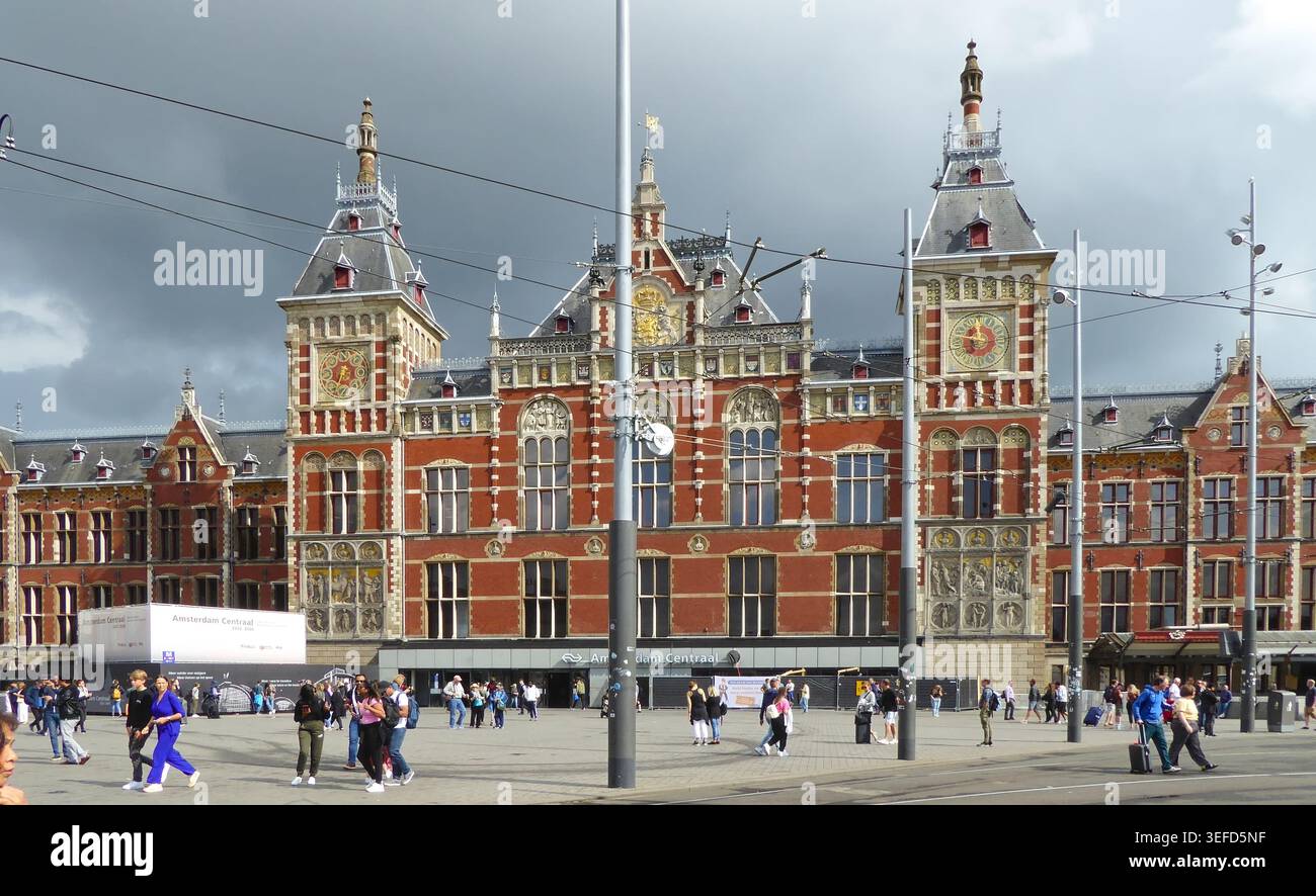 Großartiges historisches Empfangsgebäude mit Menschenmassen und einem bewölkten Himmel am Hauptbahnhof Amsterdam, Niederlande. Stockfoto