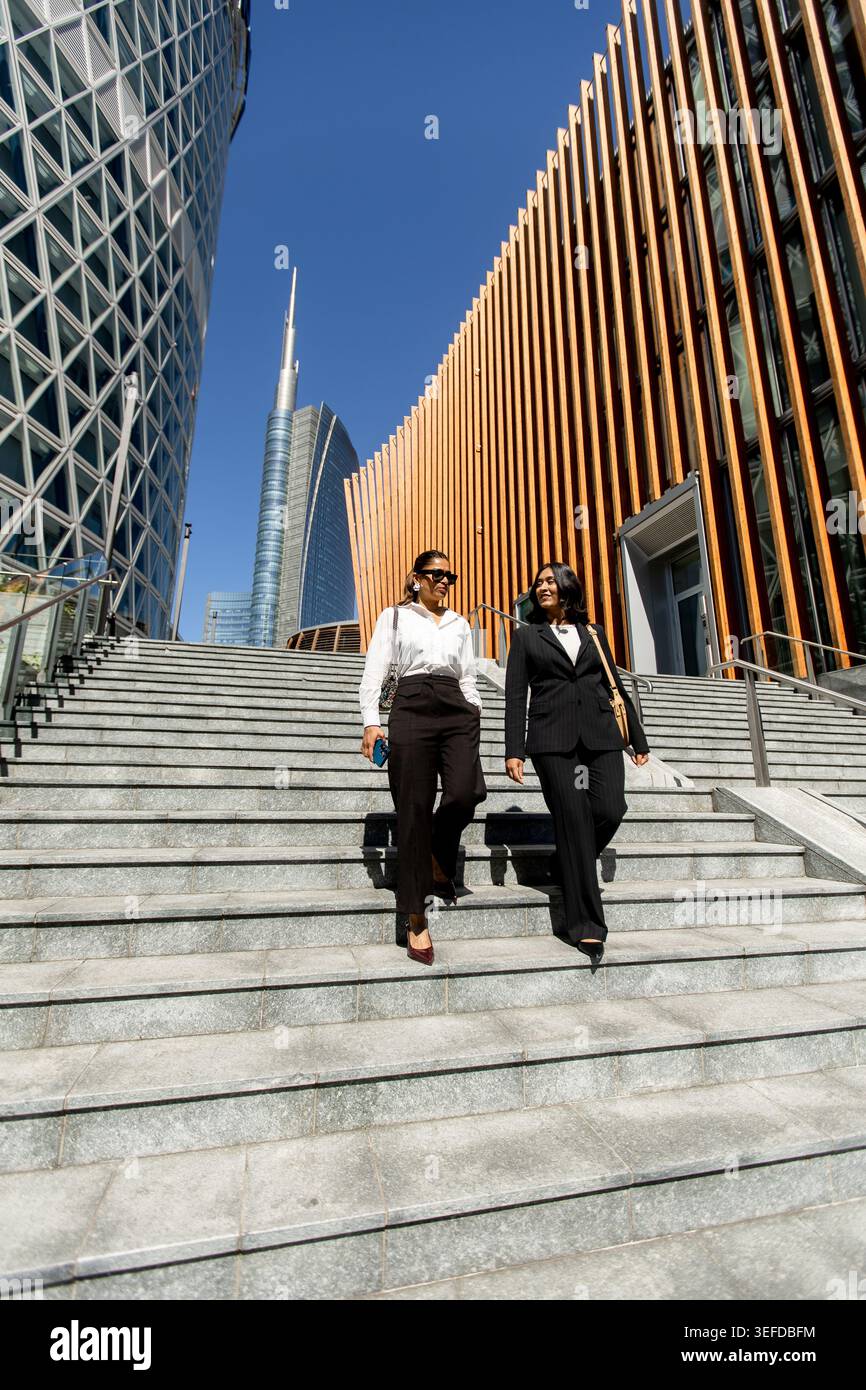 Stilvoll gekleidete Frauen steigen an einem sonnigen Tag hinab und genießen ihre urbane Umgebung. Stockfoto