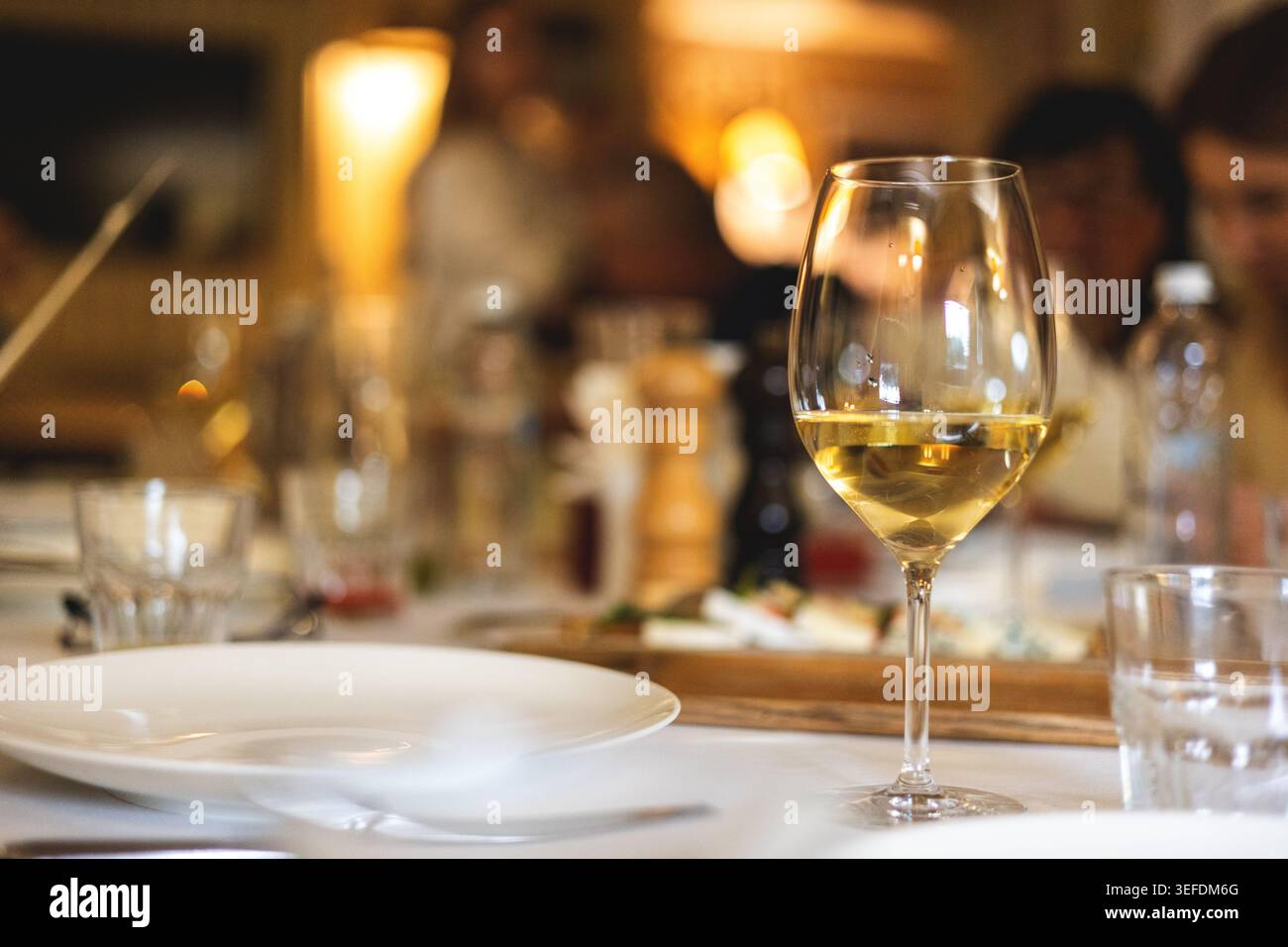 Restaurant-Atmosphäre. Ein Glas Weißwein auf einem gedeckten Tisch. Stockfoto