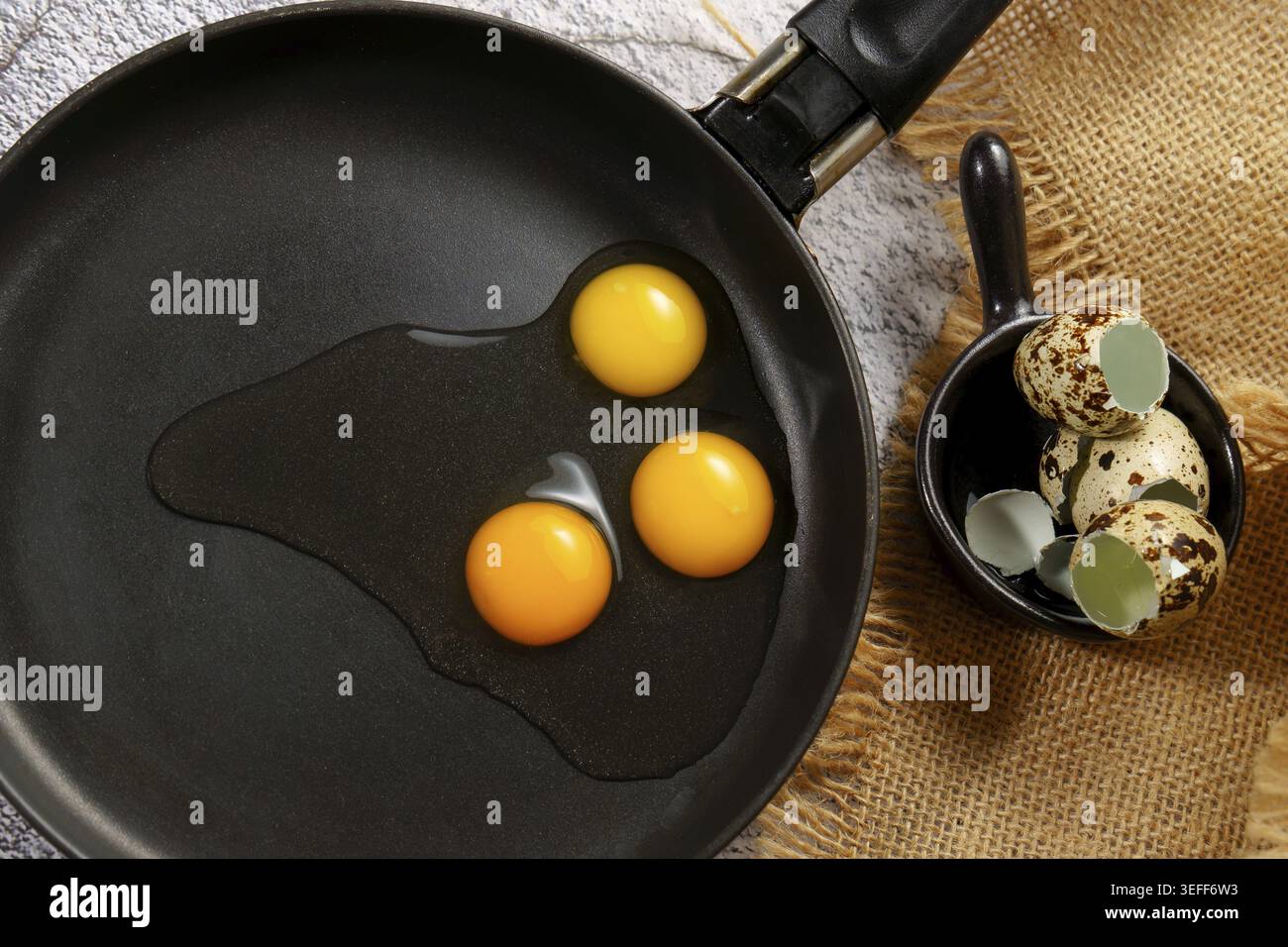 Wachteleier knacken in eine heiße Pfanne, bereit für ein gesundes Frühstück oder nahrhafte Mahlzeit in der Küche Stockfoto