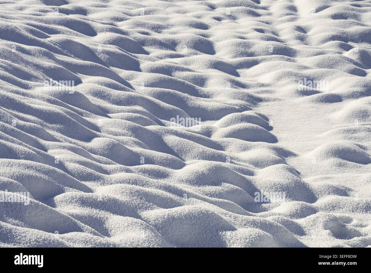 Die Textur der kleinen Schneeschwehungen auf dem Boden Stockfoto