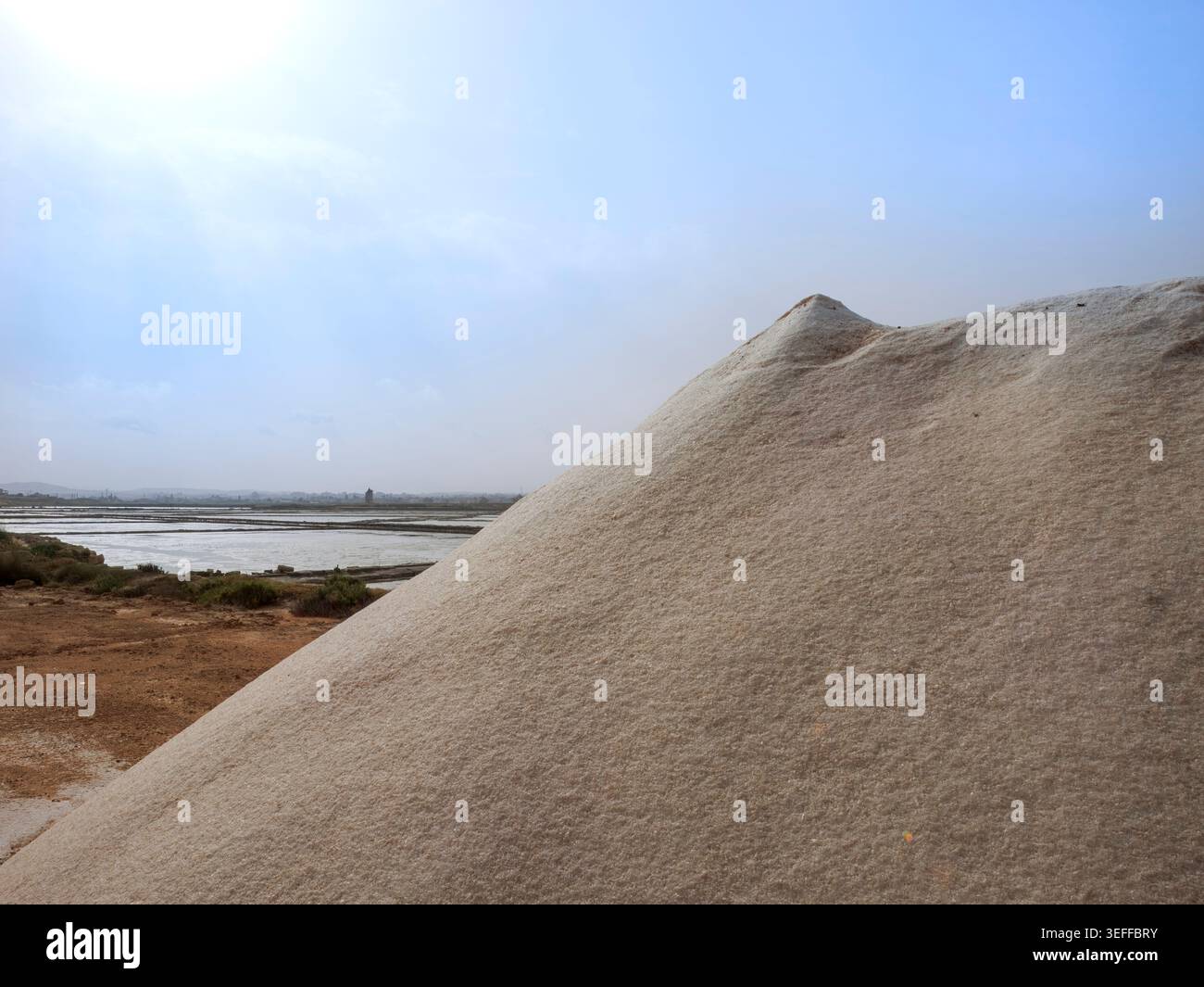 Hoch aufragende Hügel mit geerntetem Meersalz stapelten sich neben den Verdunstungsteichen der Saline Trapani auf Sizilien. Stockfoto