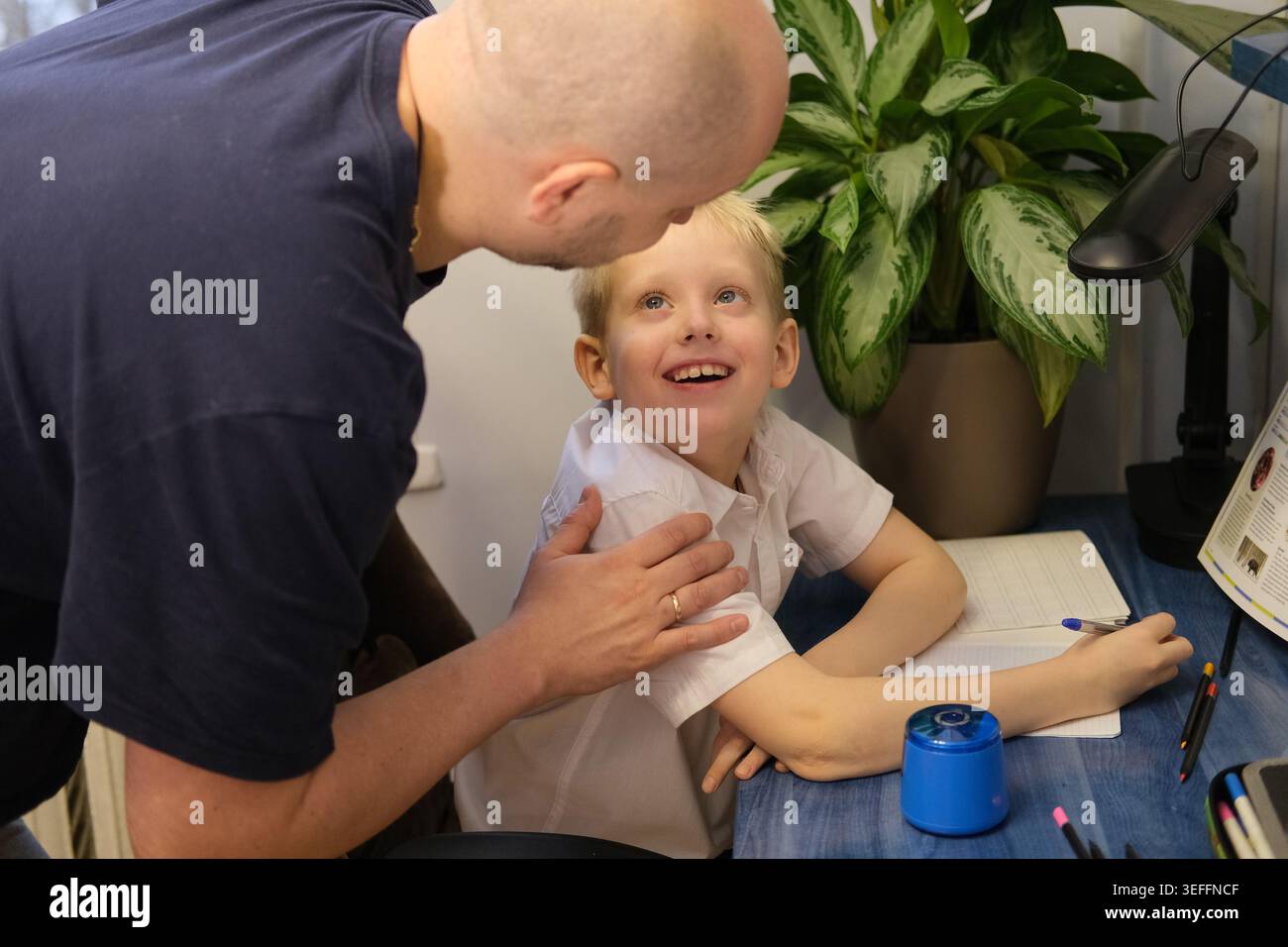 Vater hilft dem Sohn bei den Hausaufgaben, fördert das Lernen und die Bindung an die Familie Stockfoto