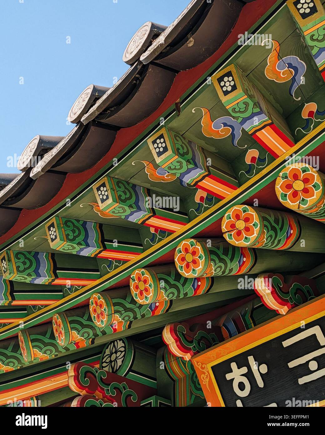 Traditionelle koreanische Danceong-Färbung auf der Dachtraufe. Nahaufnahme der Dachtraufe aus Holz mit dekorativer Farbgebung mit lebhaften Blumenmustern. Stockfoto