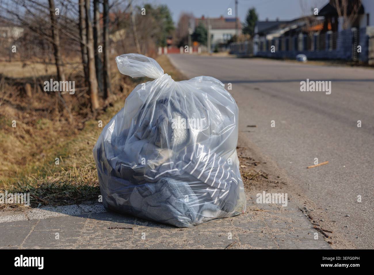 Transparente Plastiktüte gefüllt mit altem Textilabfall auf der Straße in Polen Stockfoto