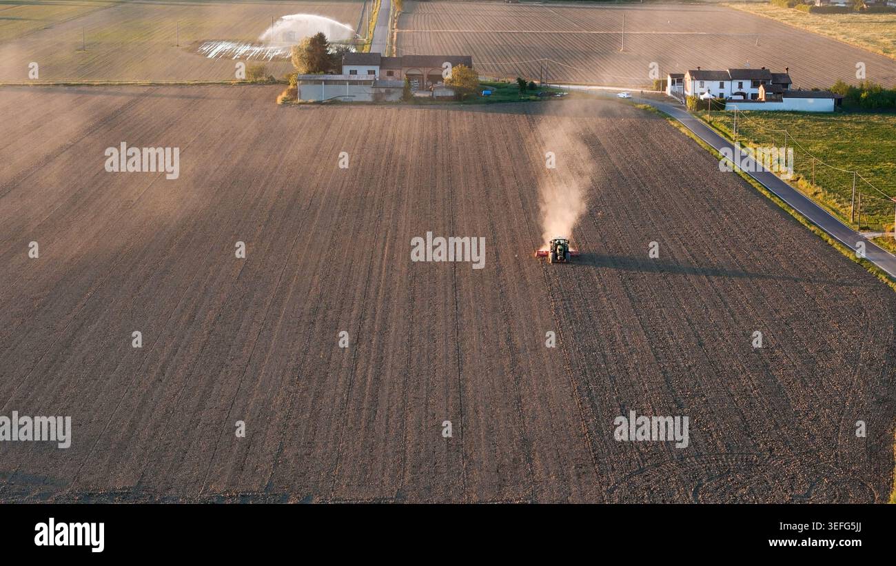 Landschaft des Po Valley bei Sonnenuntergang, die eine Bodenbearbeitung des Traktors zeigt Stockfoto
