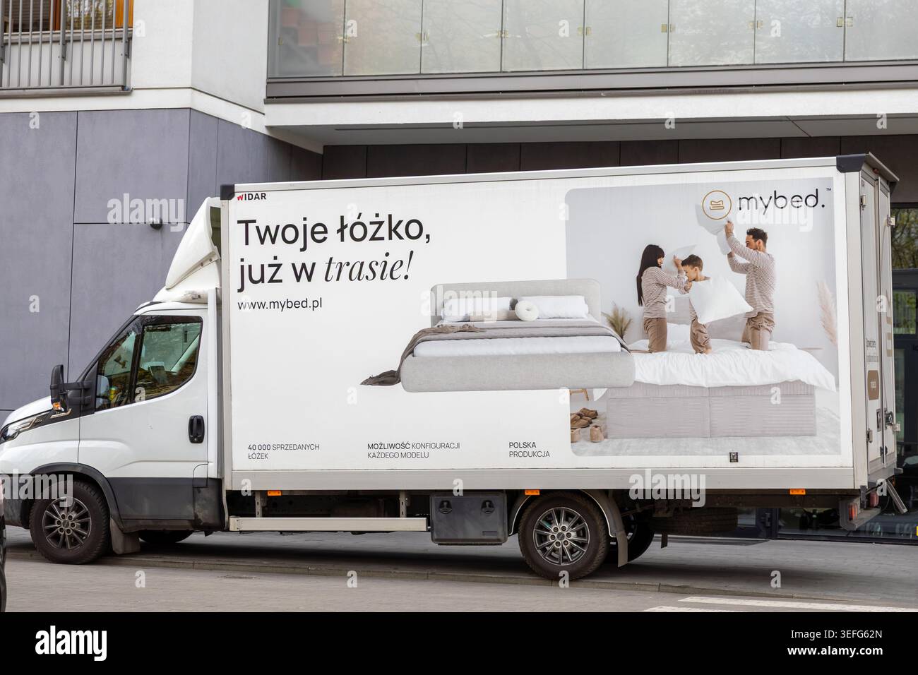 Warschau, Polen - 13. April 2026: Nutzfahrzeug mit der Marke MyBed mit Marketinggrafiken einer Familie, die auf einem Bett spielt, und die Möbel-Logisti hervorheben Stockfoto