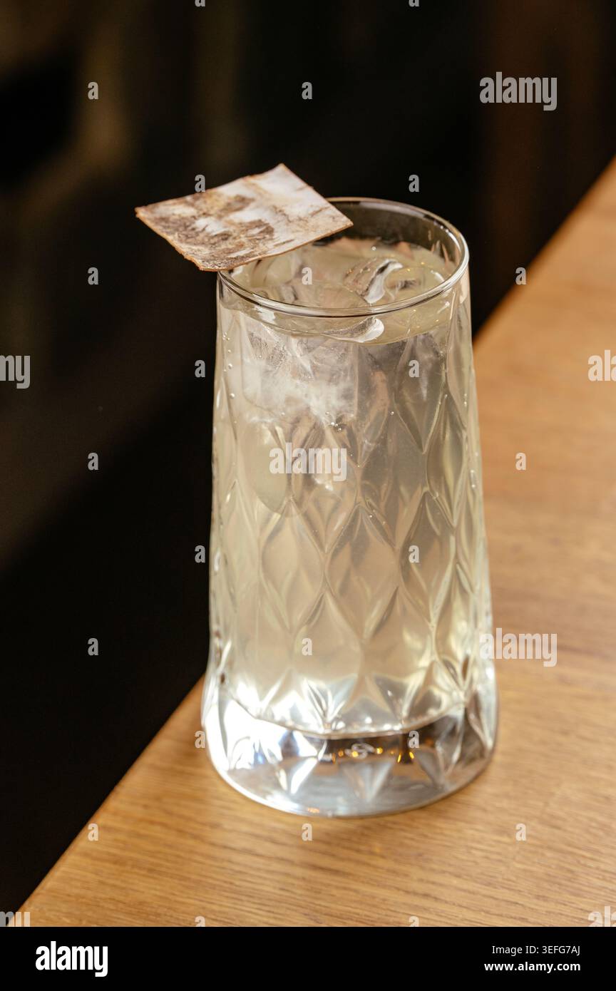 Eisiger Highball-Cocktail in einem gemusterten Glas auf Holz Stockfoto