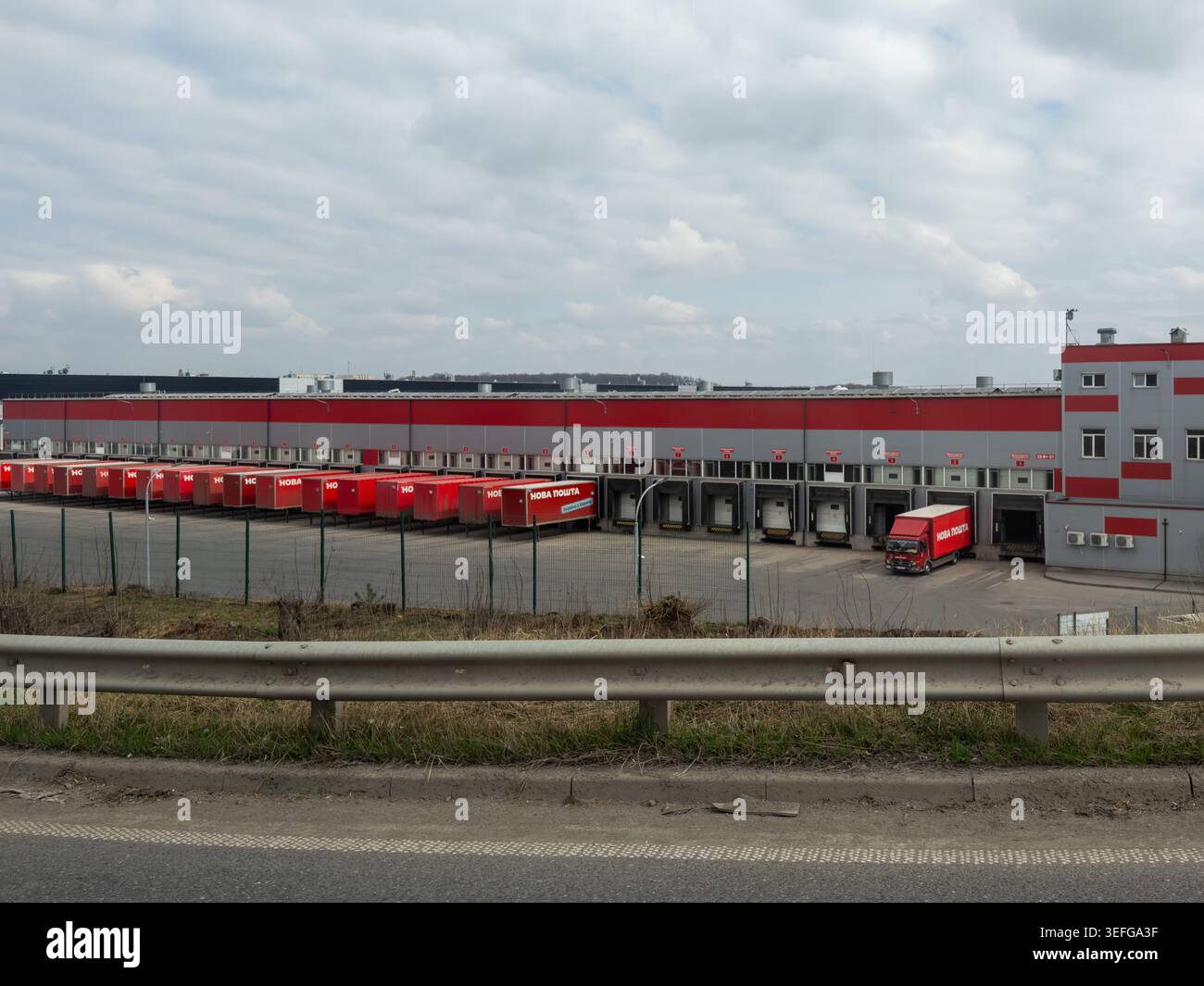 Chmelnytskyi, Ukraine - 30. März 2026: Das Lagerhaus Nova Poschta verfügt über mehrere Ladebuchten und geparkte rote Transportwagen für eine effiziente Nutzung Stockfoto