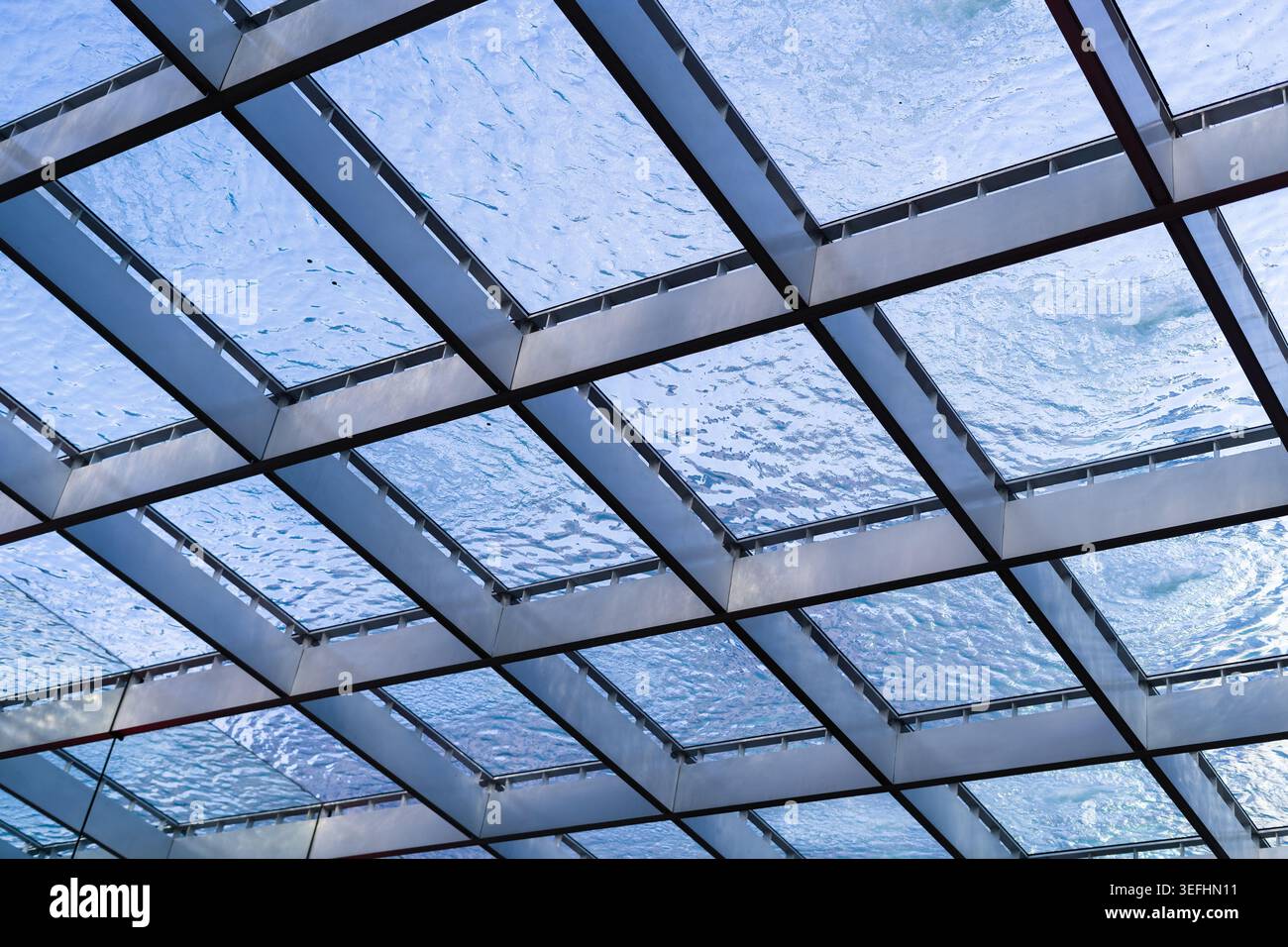 Blick auf eine moderne Glasdecke mit Wasser, das über die Gitterstruktur unter einem klaren blauen Himmel in Bratislava, Region Bratislava, Slowakei fließt. Stockfoto