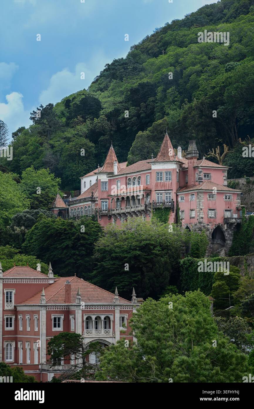 Bezauberndes Foto eines rosafarbenen historischen Palastes, umgeben von dichten Wäldern in Sintra, Portugal, das den märchenhaften Charme dieser UNESCO-Stätte einfängt. Stockfoto