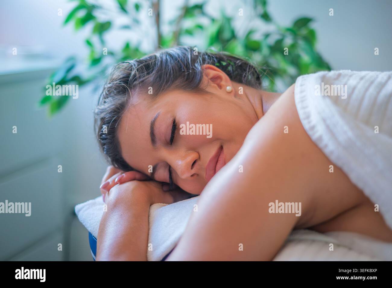 Eine Frau genießt eine beruhigende Massage in einem Beauty-Spa, umgeben von ruhiger Einrichtung und entspanntem Ambiente für ultimative Entspannung. Stockfoto