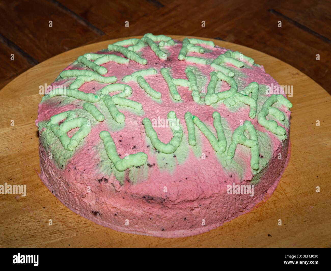 Hausgemachte pinkfarbene Geburtstagskuchen mit grünen Zuckerglasbuchstaben, die alles Gute zum Geburtstag schreiben Luna hausgemachte pinkfarbene Geburtstagskuchen mit grünen Zuckerglasbuchstaben Spellin Stockfoto
