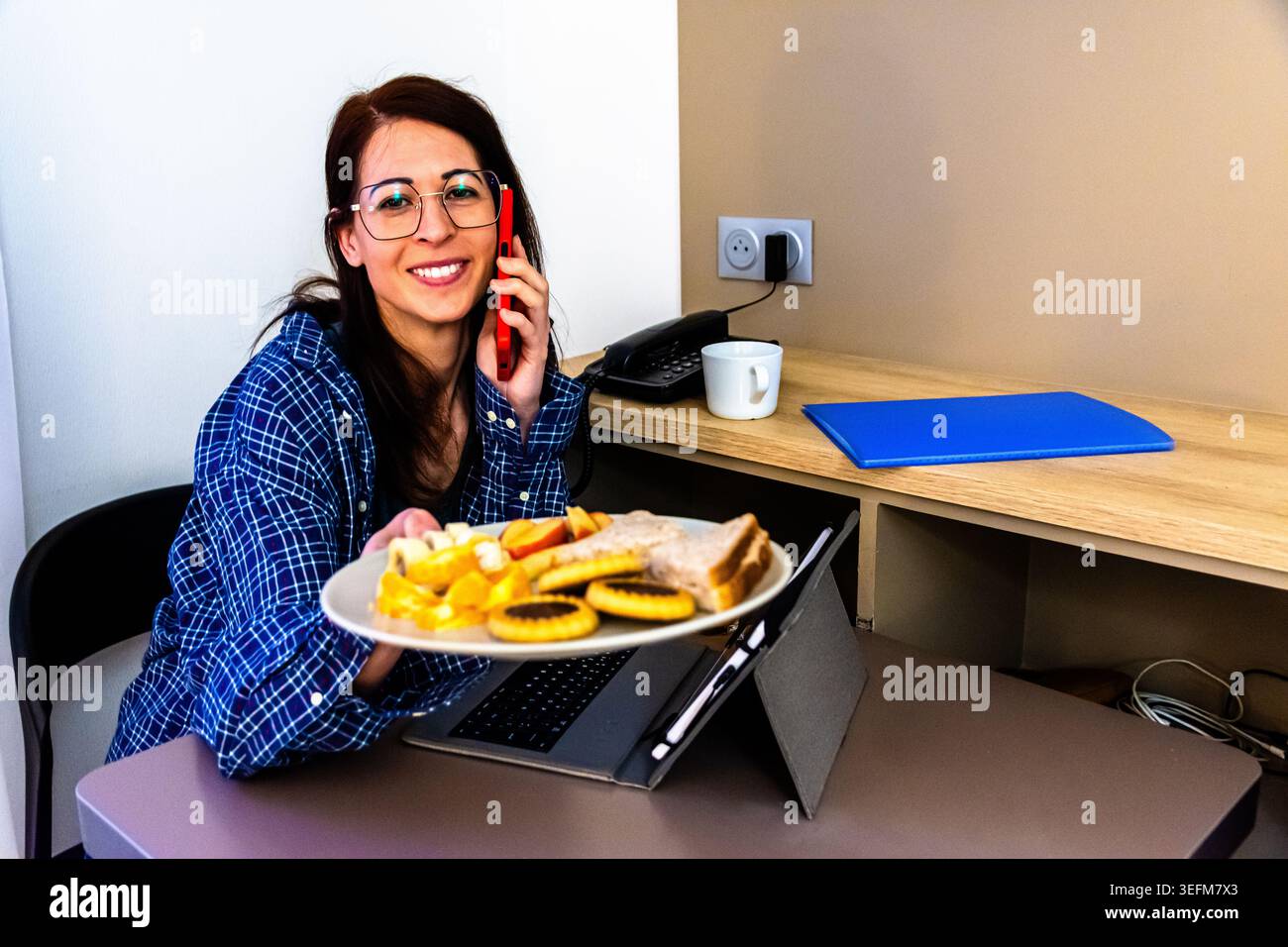 Frau, die während des morgendlichen Routinefrühstücks aus der Ferne arbeitet Stockfoto